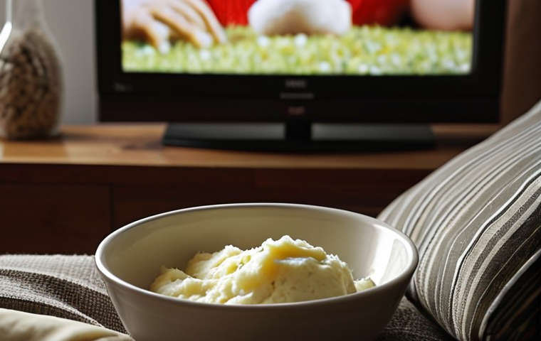 **
A close-up shot of someone relaxing on a sofa, with a cold compress on their cheek, watching a movie on TV. Soft lighting and a cozy atmosphere. A bowl of mashed potatoes and a glass of water are on a nearby table. Focus on conveying comfort and rest.
**